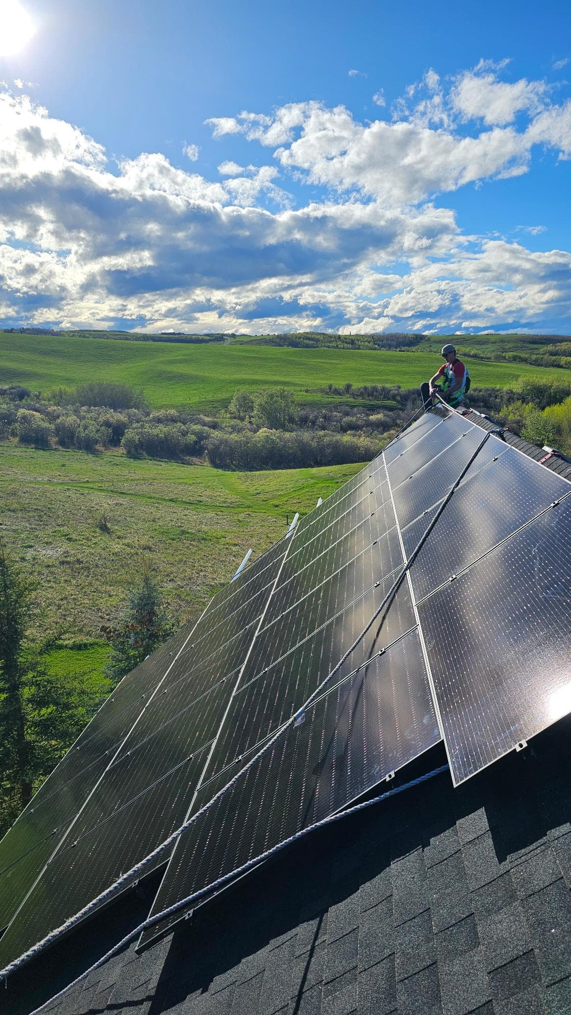Solar installer working on rooftop with Alberta countryside views