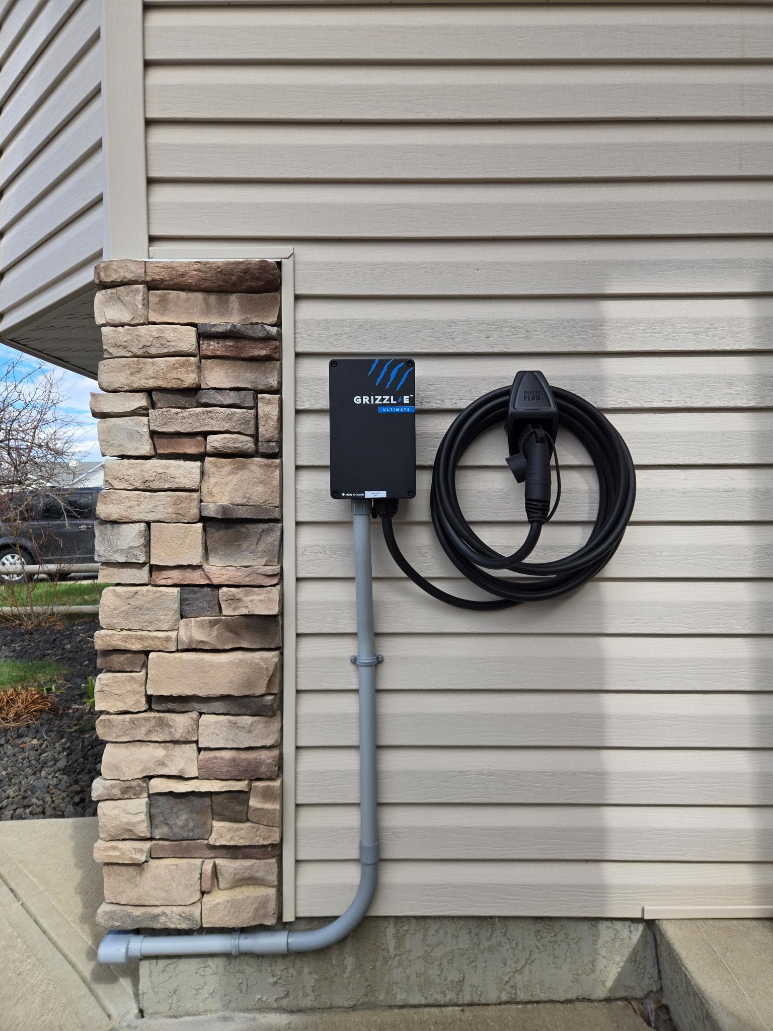 Grizzl-E Ultimate Level 2 EV charger installed on the exterior of a Calgary home, mounted beside vinyl siding with rigid conduit