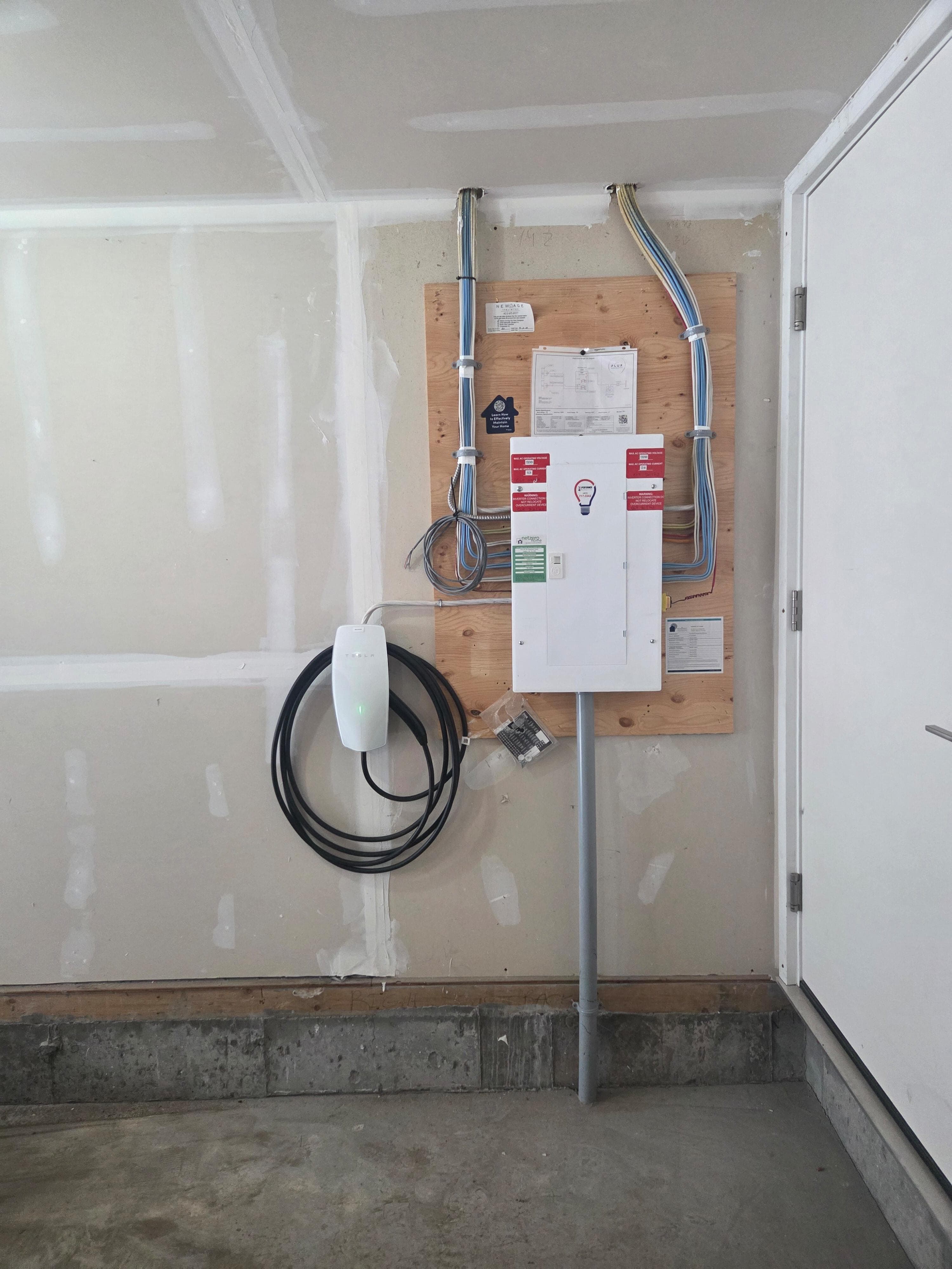 Tesla Wall Connector installed in a new-build Calgary garage beside the main electrical panel